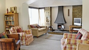 A cozy living room with a fireplace, a television, and a bookshelf. - 4 bedroom accommodation in Grassington (Grassington)