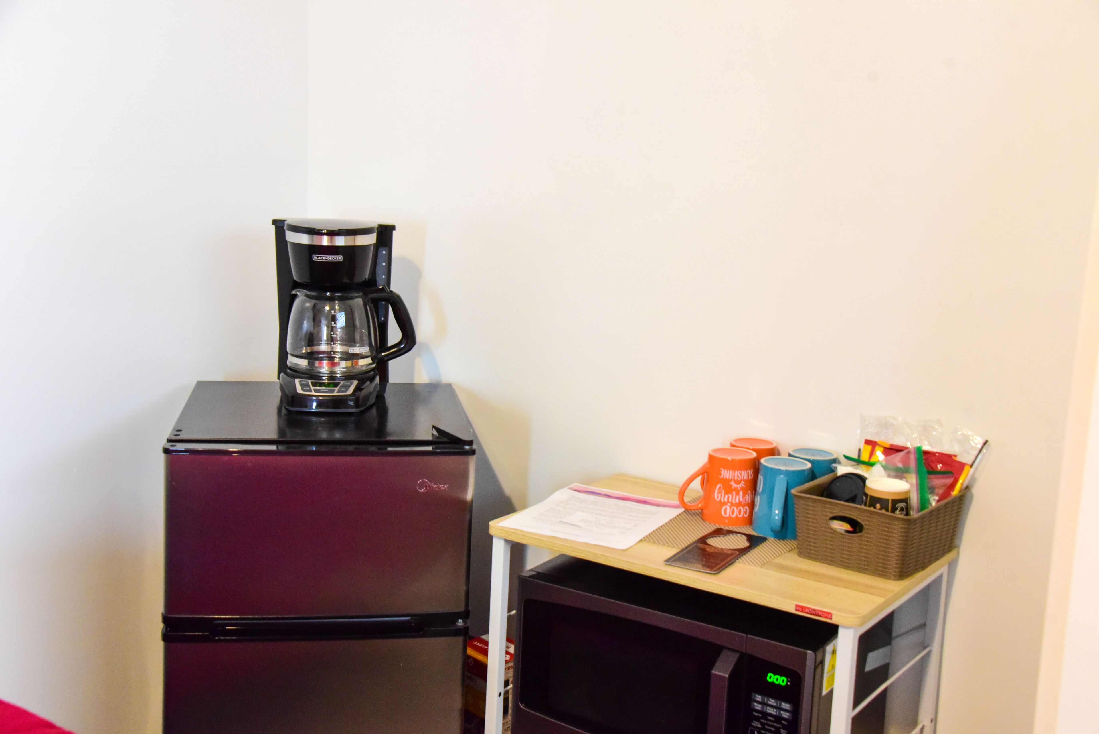 A compact kitchenette with a refrigerator, microwave, and coffee maker.