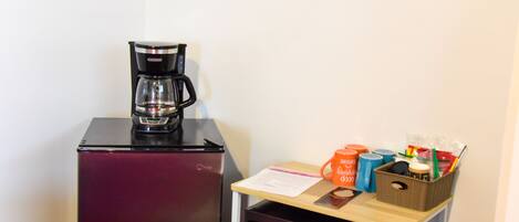 A compact kitchenette with a refrigerator, microwave, and coffee maker.