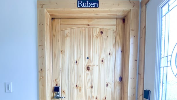 Eine Holztür mit Namensschild mit dem Schriftzug „Ruben“ und einem Schlüsselfeld.