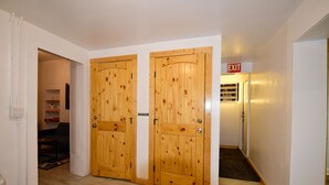 A hallway with wooden double doors, a sign indicating an exit, and a carpeted floor. - Carmen's Marfa Hotel/Leticia 2 Queen Beds (Marfa)