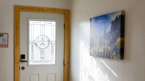 Una habitación con una puerta blanca, un tapete colorido, un cuadro en la pared y una ventana con forma de estrella.