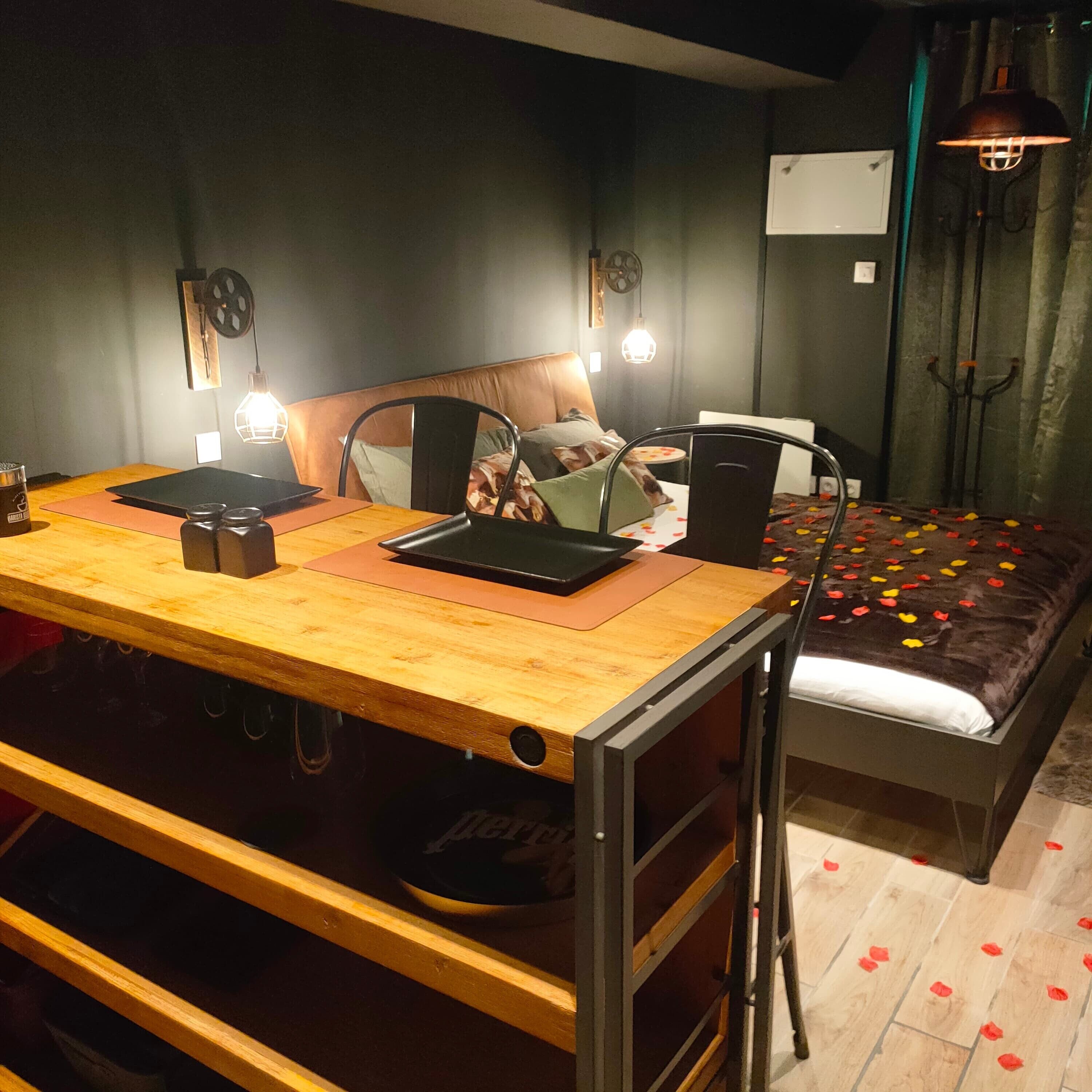 A bedroom with a bed, a desk with a laptop, a chair, and a wardrobe.