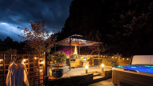An outdoor patio area with a hot tub, seating, and a covered seating area.