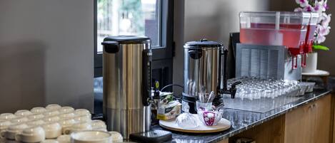 Una estación de café con varias cafeteras, un dispensador de agua y una variedad de tazas y platos.