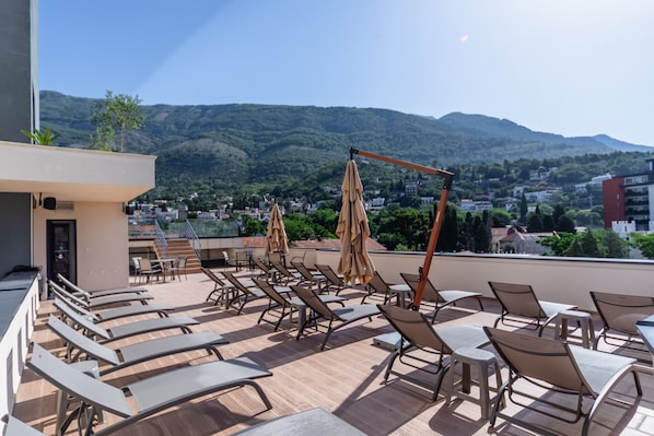 A rooftop terrace with sun loungers and umbrellas, overlooking a mountainous landscape. - N Hotel (Sutomore)