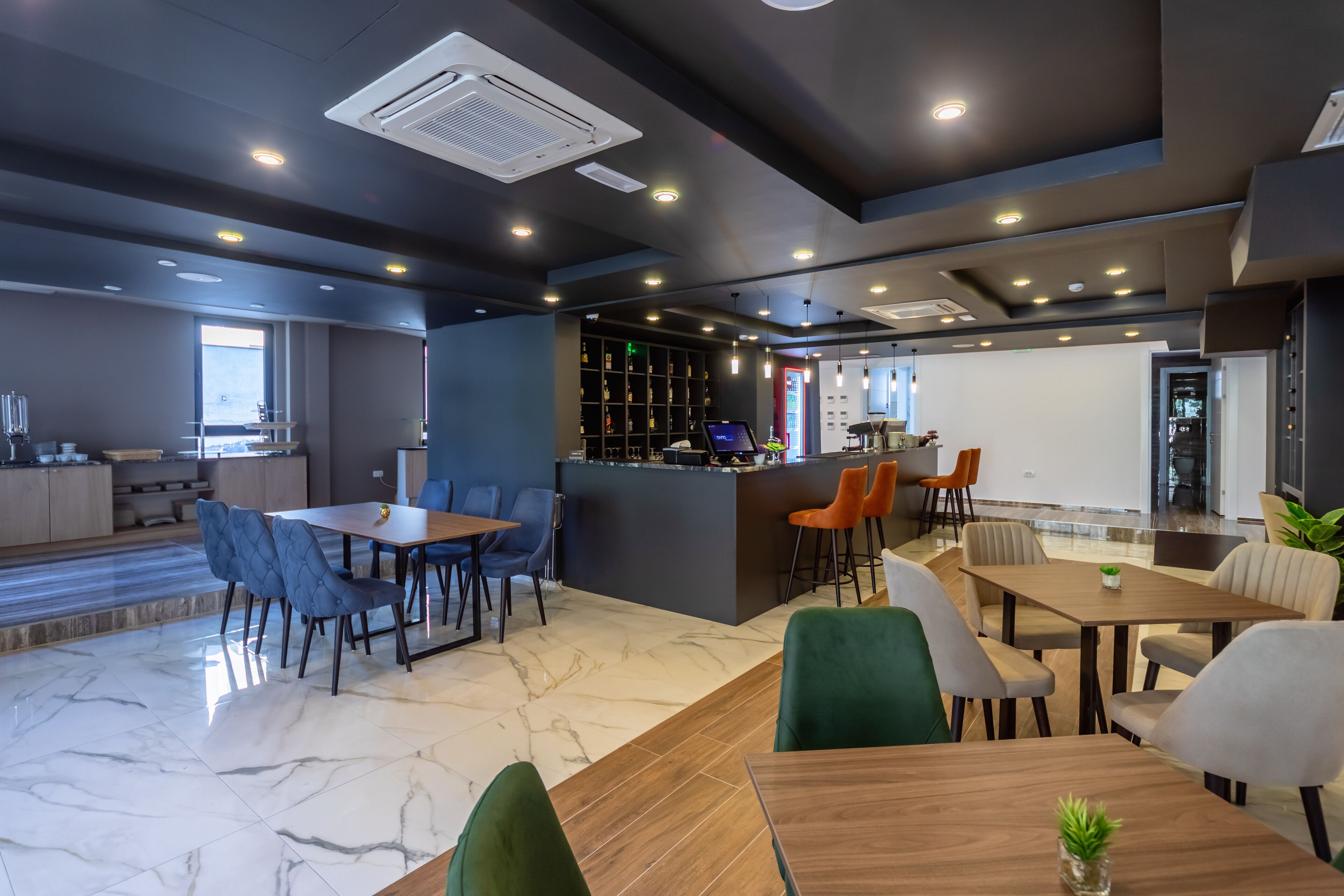 Eine moderne Hotelhalle mit Marmorböden, einer Bar und Sitzgelegenheiten.