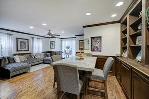 Relax in this inviting living area with a large sofa, dining table, and bookshelf.