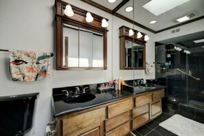 Bathroom features a double sink vanity with a countertop and cabinetry, two mirrors, and a toilet.