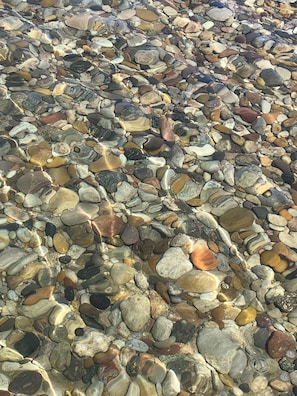 A close-up of a pebble beach with variously shaped and colored stones. - Property for Tornado Watchers! (Springfield)