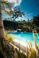 Una piscina al aire libre, sombrillas, sillones reclinables de piscina