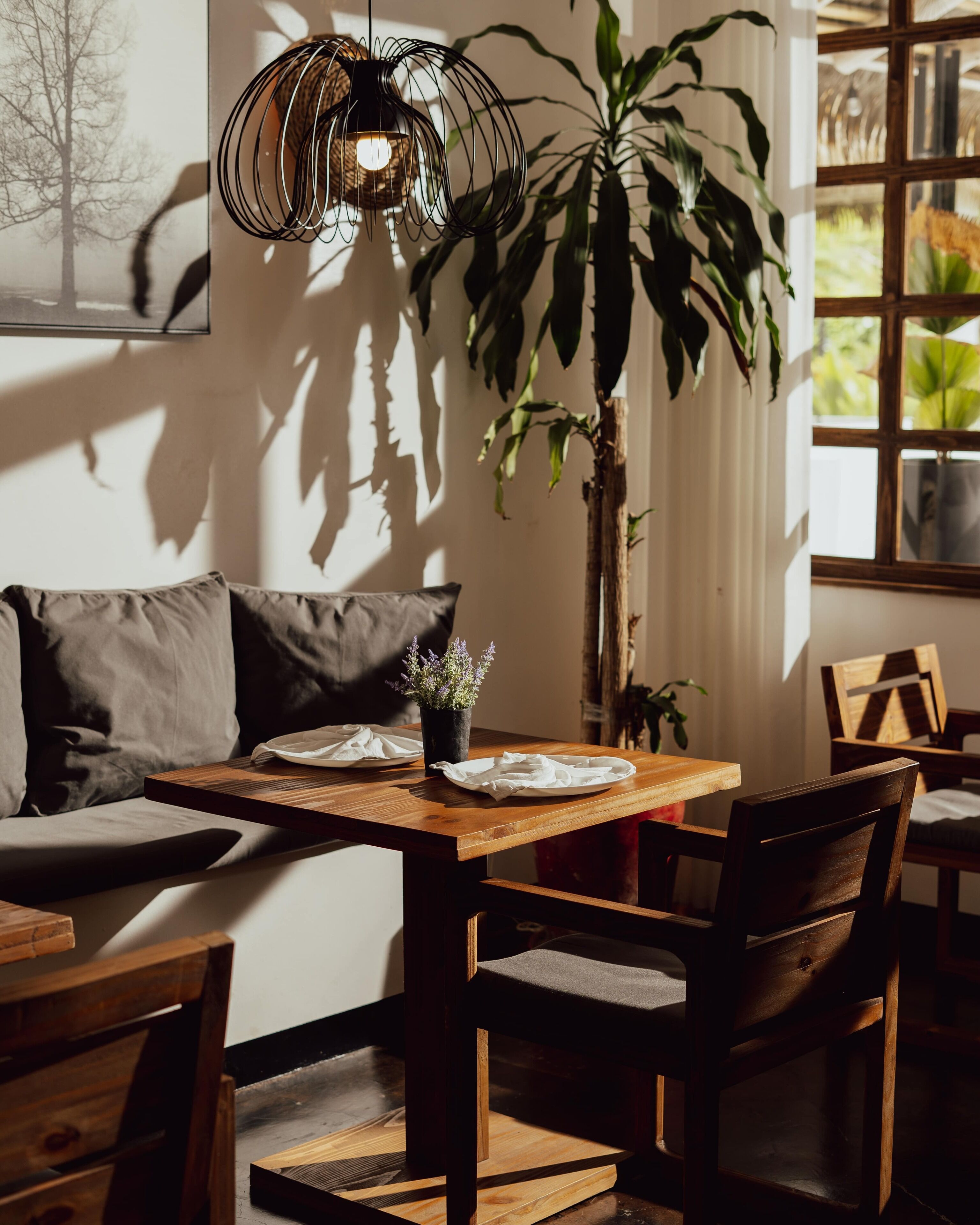 Een gezellige eethoek met een houten tafel, stoelen en een hanglamp.