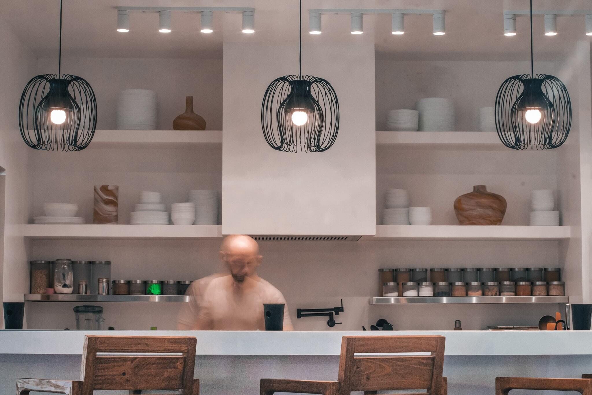 A modern kitchen with pendant lights, white cabinets, and various kitchen utensils.