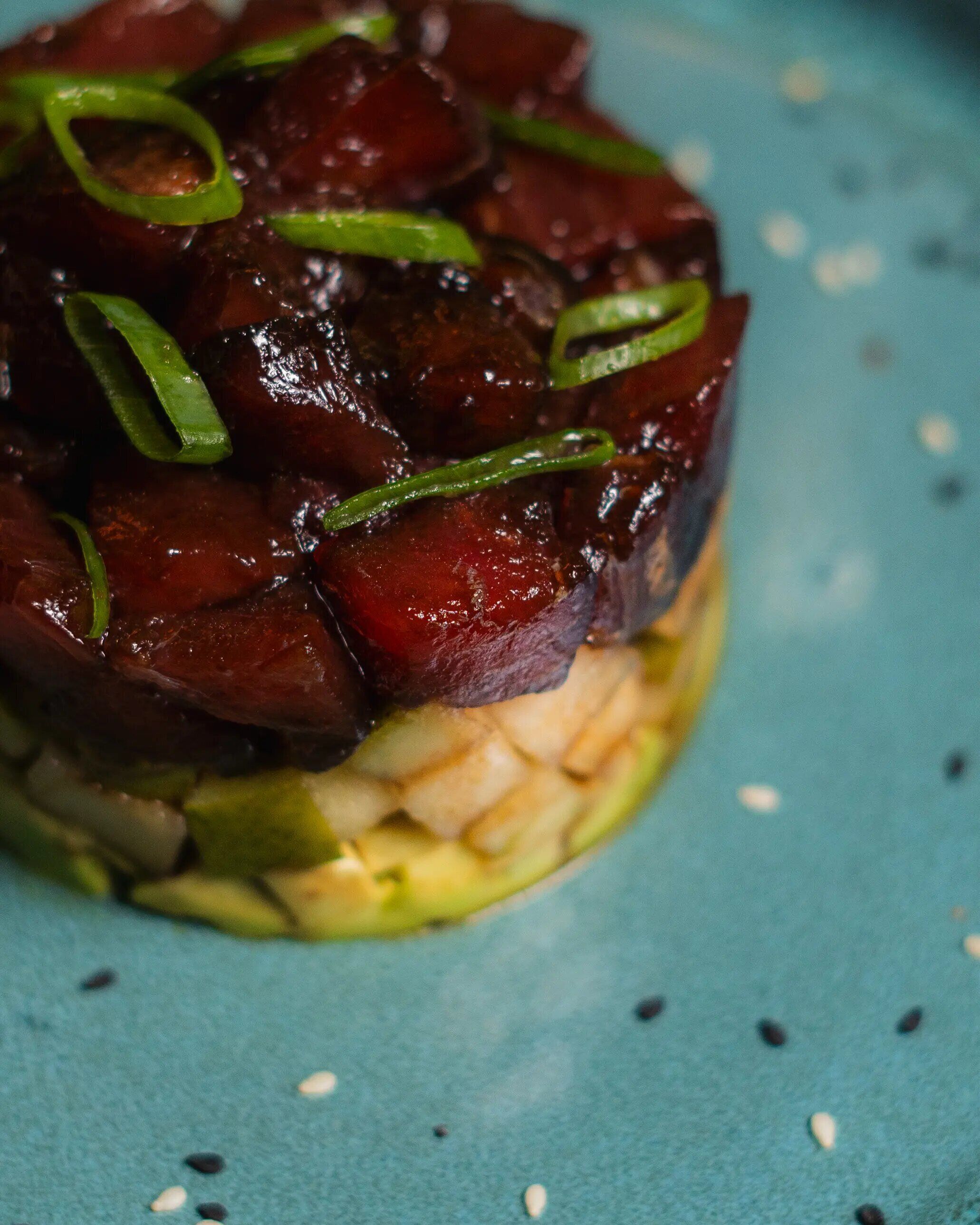 A dish with a dark sauce and green garnish on a blue plate.