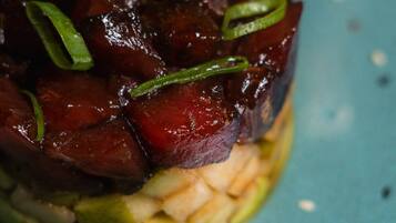 A dish with a dark sauce and green garnish on a blue plate.