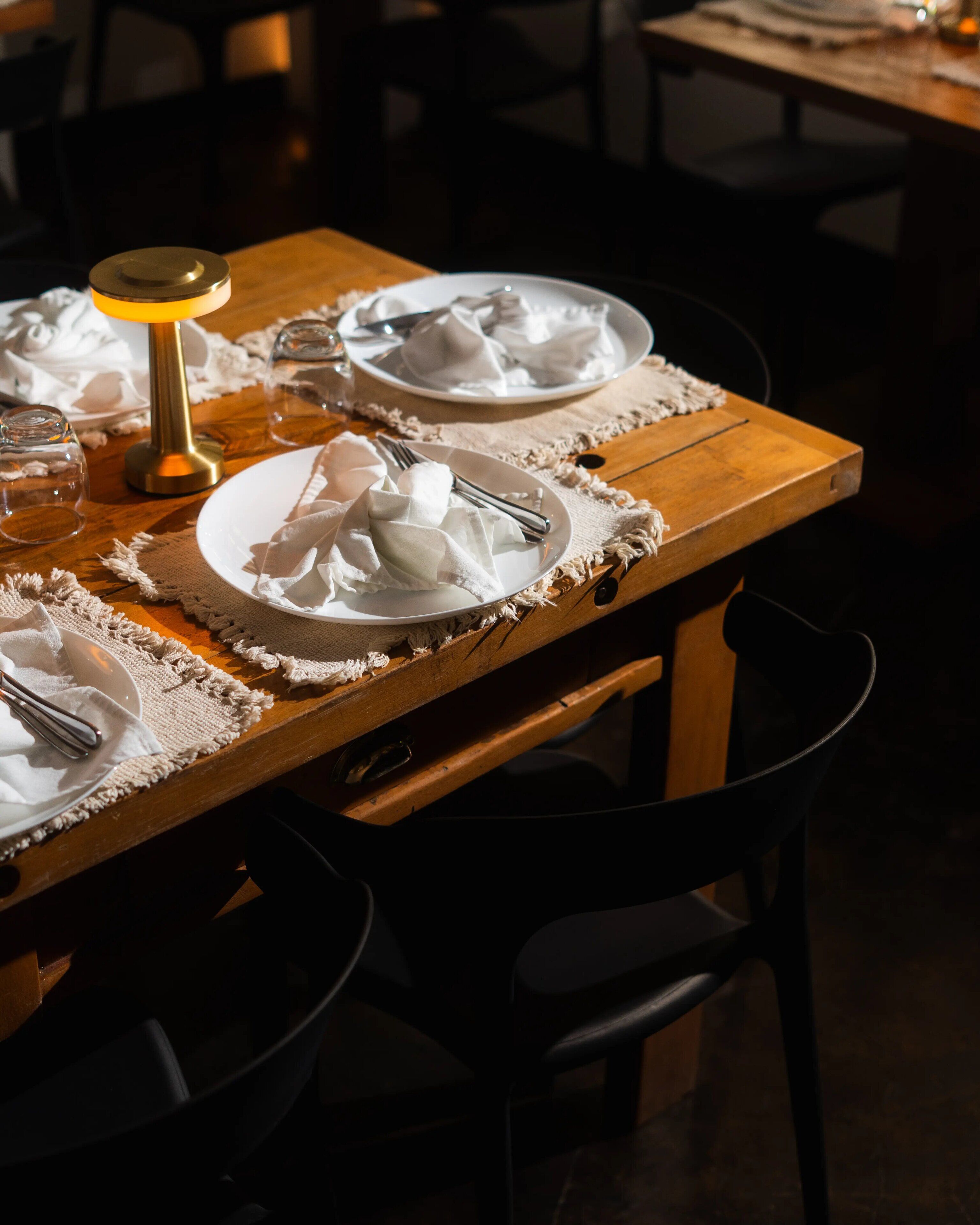 A dining table set with white plates, silverware, and a candle.