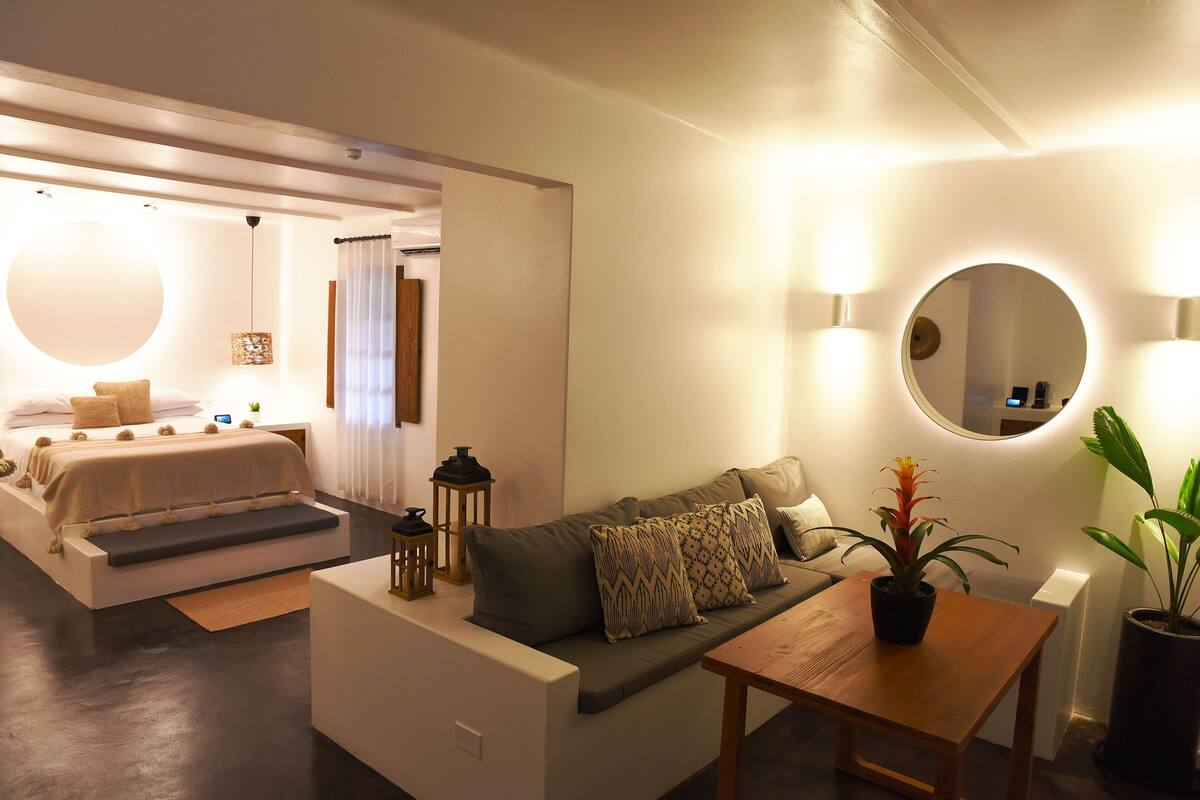 Ein modernes Hotelzimmer mit Bett, Sofa und einem kleinen Tisch mit Blumentopf.