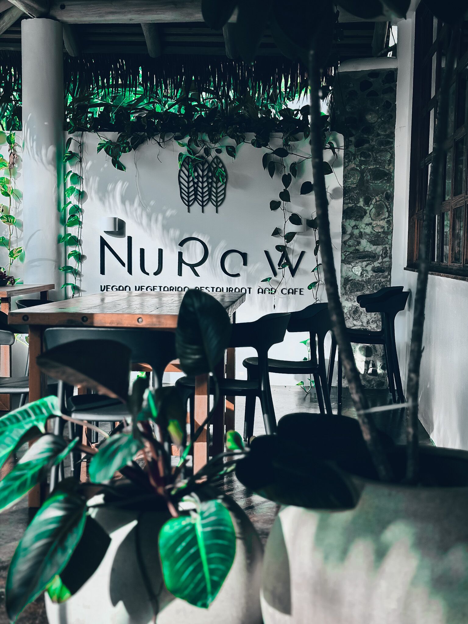 A restaurant interior with a sign reading "NURCOW VEGAN VEGETARIAN RESTAURANT AND CAFE".
