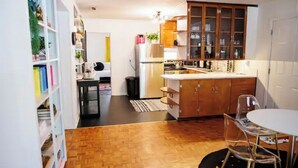 Eine kleine Küche mit Holzschränken, einem Kühlschrank und einem Essbereich mit Tisch und Stühlen.
