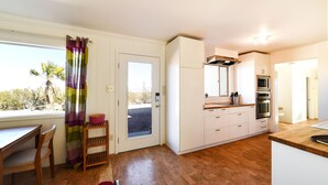 A kitchen with white cabinets, a wooden countertop, and a built-in oven. - Joshua Tree Hot Springs House (Twentynine Palms)