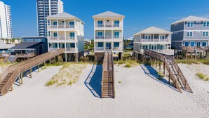A beachfront hotel with multiple-story buildings, wooden walkways, and a sandy beach.