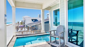 A poolside area with a view of the ocean, a deck with chairs, and a building in the background. - Beachfront Luxury | Private Pool | Elevator | Pet Friendly (Gulf Shores)