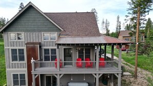 Una casa de dos pisos con balcón, jacuzzi y zona de estar exterior.
