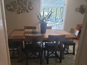 A dining area with a wooden table and chairs, a potted plant, and a decorative wall piece.