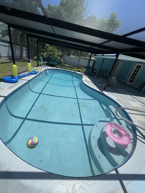 A swimming pool with a slide, a lounge chair, and a covered patio area.