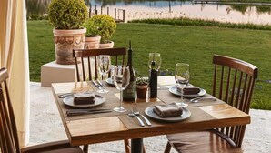 An outdoor dining area with a table set for two, overlooking a lake and hills. - HOTEL VIÑEDOS SANTA CATALINA (San Miguel de Allende)