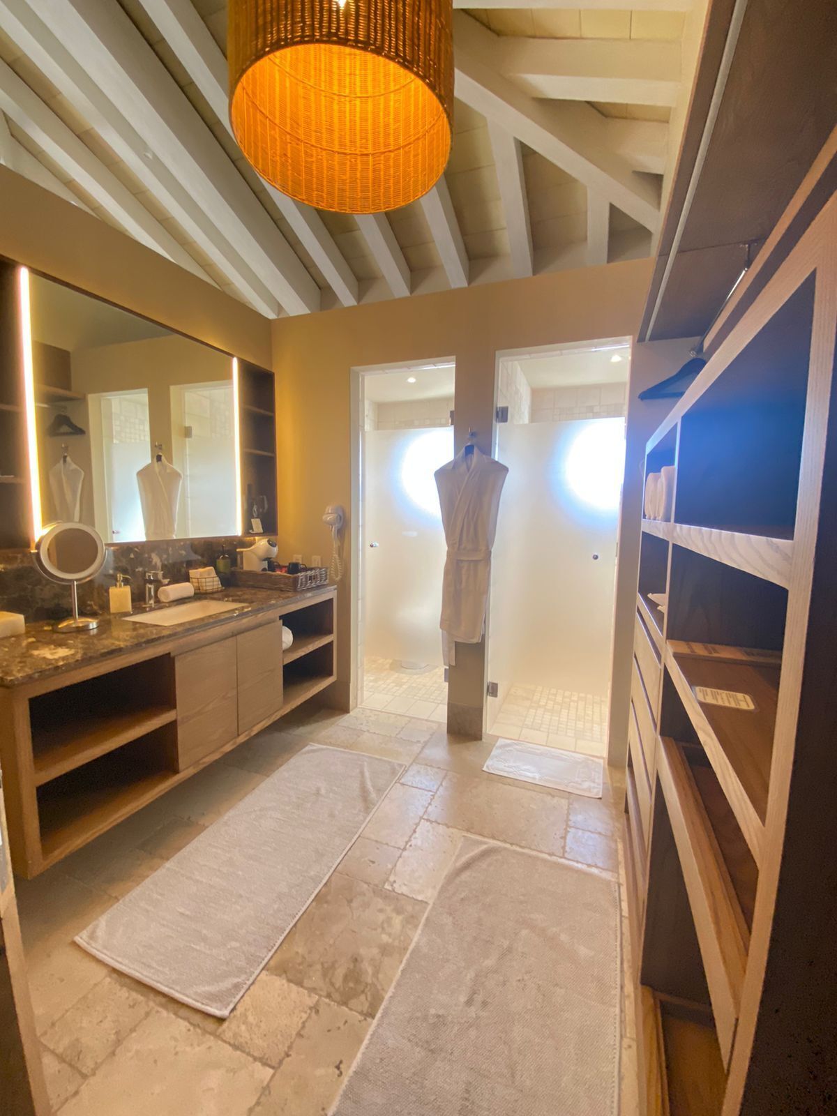 A modern bathroom with a large mirror, vanity, and a hanging light fixture.