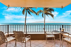 Enjoy ocean views from this balcony with a table for two and comfortable seating.
