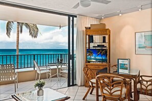 Enjoy ocean views from the balcony, featuring a glass table, vase of flowers, and comfortable seating.