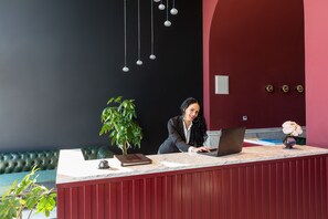 A reception desk with a laptop, a plant, and a vase of flowers. - Palacio Del Mar (Rafajlovici)