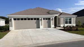 A single-story house with a garage, a driveway, and a well-maintained lawn. - Ultra clean designer home in The Villages (3-bed) (Wildwood)
