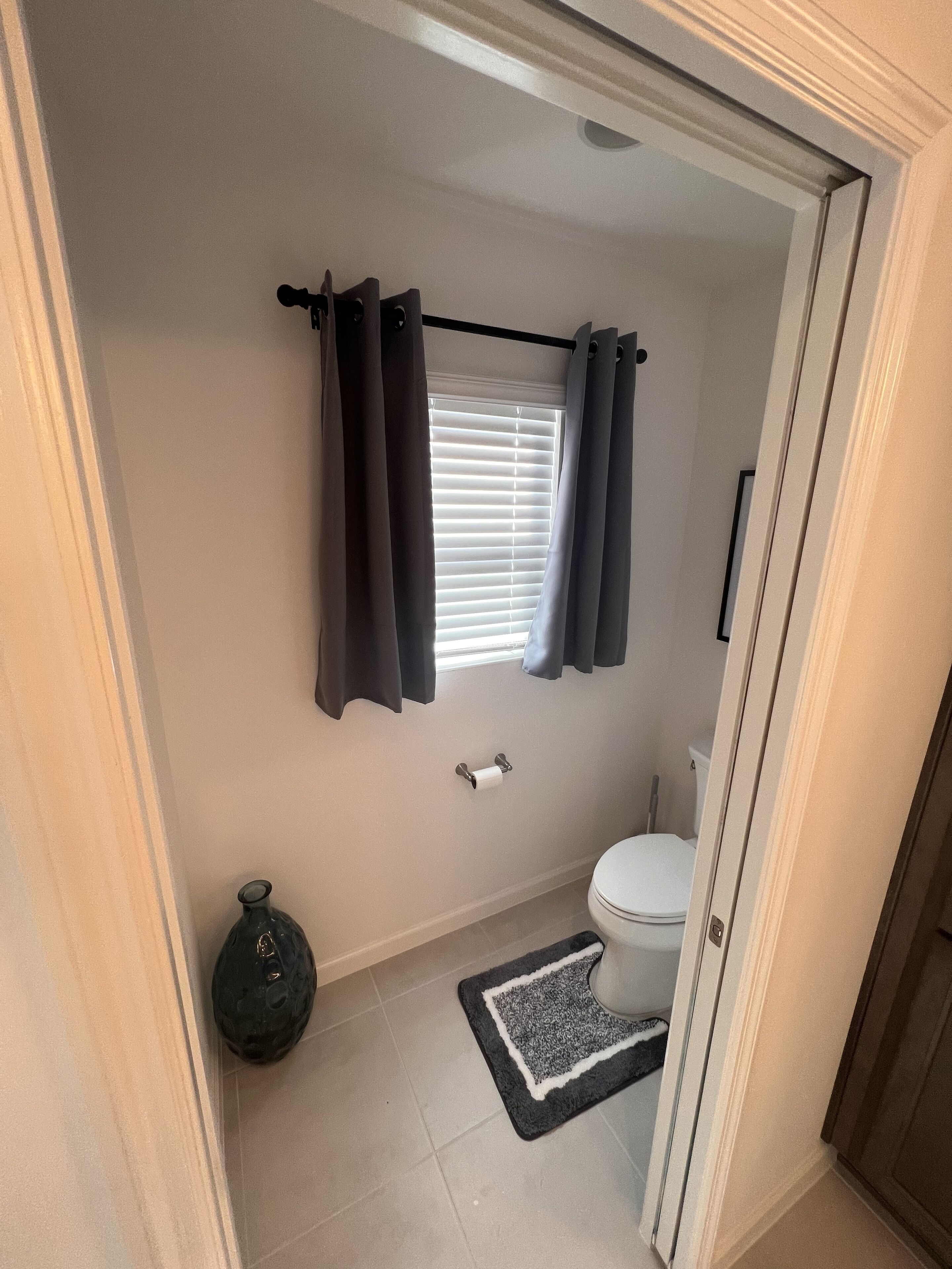 Ein Badezimmer mit Toilette, Duschvorhangstange, Handtuchhalter und einer kleinen Fußmatte.