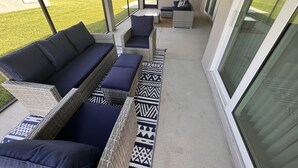 A covered patio area with wicker furniture and a patterned rug. - Ultra clean designer home in The Villages (3-bed) (Wildwood)