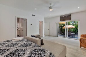 Une chambre spacieuse avec un grand lit, un canapé et une vue sur un patio extérieur.