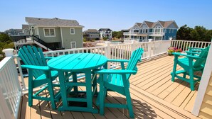 A wooden deck with turquoise chairs and a table, overlooking a residential area with houses. - Oceanside, Private Pool, Close to the beach! OS1F, La Maison de la Mer (Corolla)