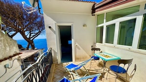 Ein Balkon mit Meerblick, ein Tisch mit Stühlen und eine Tür zum Innenbereich.