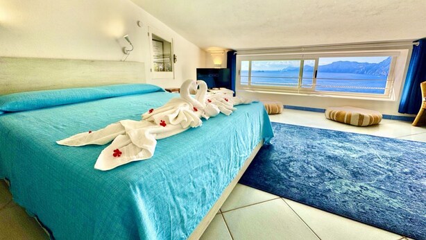 Ein Hotelzimmer mit einem großen Bett, Meerblick und einem Vorhangfenster.