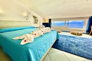 A hotel room with a large bed, a view of the sea, and a window with curtains. - The Mansarda amazing Sea View (PRAIANO)