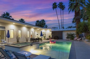 A modern pool area with a floating flamingo, lounge chairs, and palm trees.