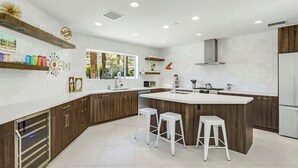 Una cocina moderna con una isla central, armarios de madera y encimeras blancas.