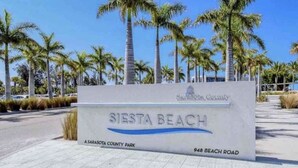 A sign for Siesta Beach, indicating it is a Sarasota County park located at 948 Beach Road.