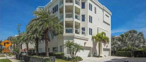 A multi-story building with balconies, palm trees, and a clear sky.