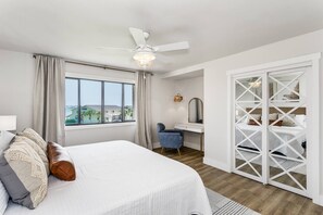 Un dormitorio con cama, escritorio, silla, armario y ventilador de techo.