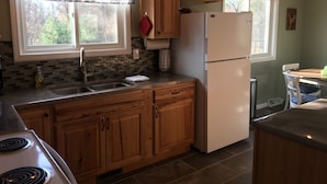 Una cocina con armarios de madera, un refrigerador blanco, un lavamanos y una estufa.