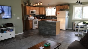 Una cocina moderna con armarios de madera, una isla central y un comedor con mesa y sillas.