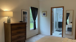 A bedroom with a bed, dresser, lamp, framed pictures, and a door leading to a bathroom. - Spacious house in serene peaceful setting 15 min from Lake Crescent&Crescent Bch (Port Angeles)